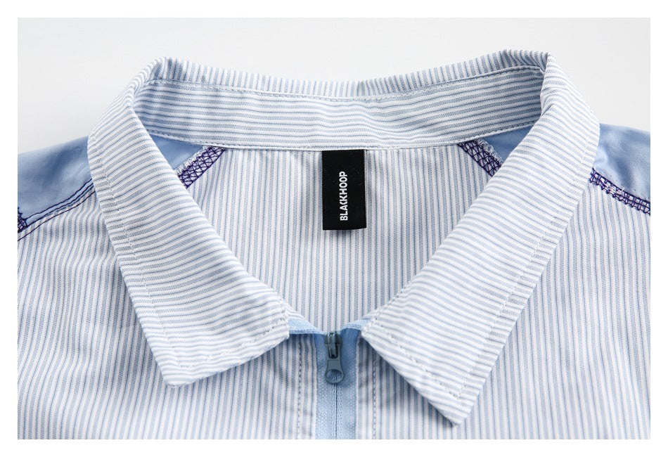 Close-up of a light blue and white striped shirt collar, zipper, shoulder seams, and neck label.