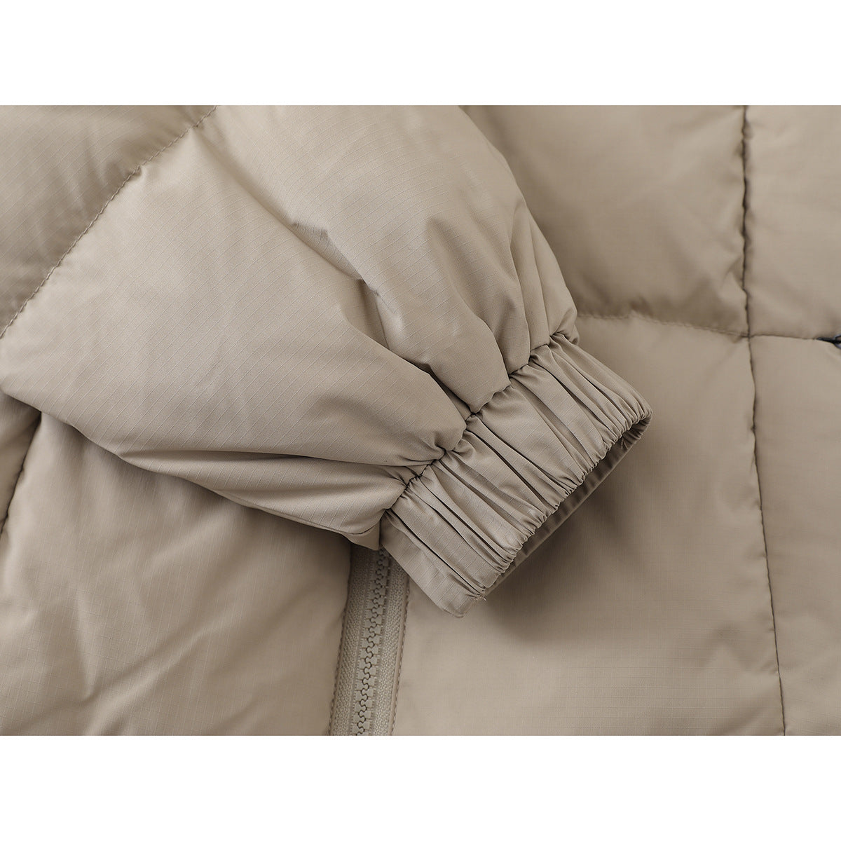 Close-up of the beige jacket's sleeve and gathered elastic cuff.