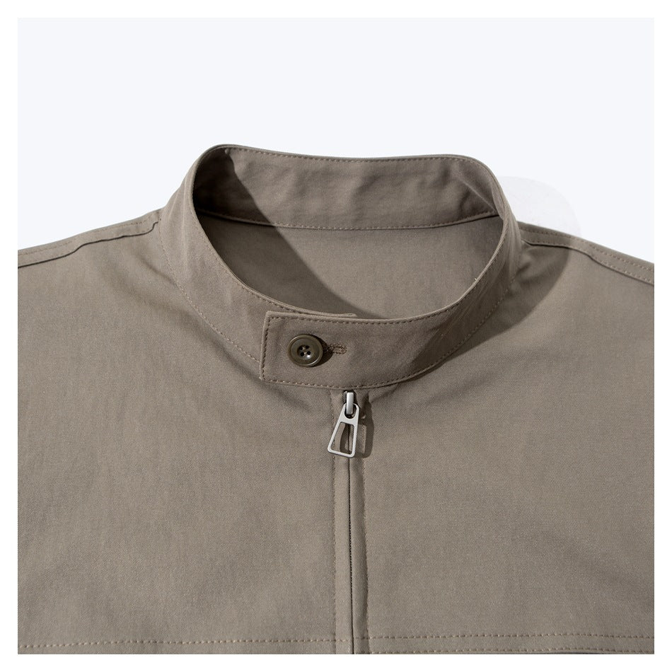 Close-up of a taupe jacket's stand collar, button tab, and front zipper.