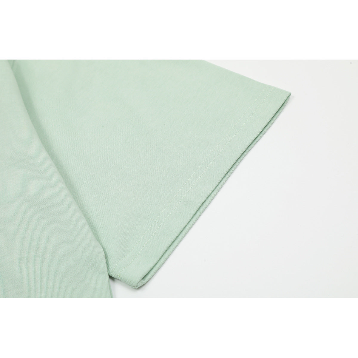 Close-up of the pale mint T-shirt’s short sleeve and double-stitched hem.