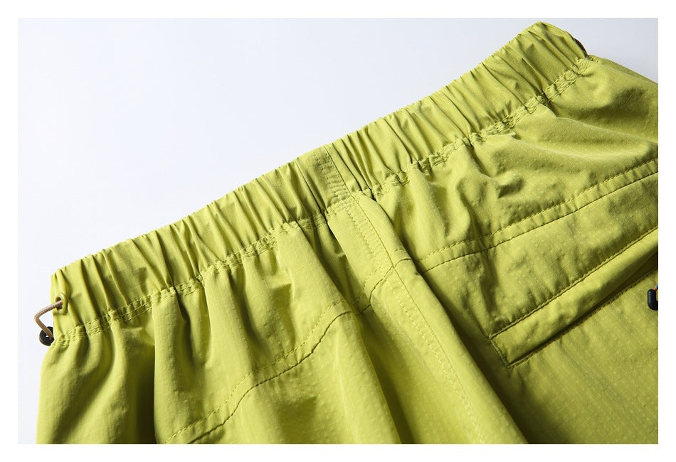 Close-up of the lime-yellow shorts' gathered elastic waistband and side drawcord eyelet.