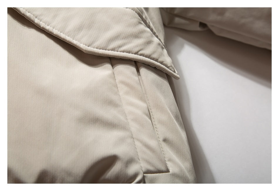 Close-up of a beige jacket's side pocket beneath a pointed flap.
