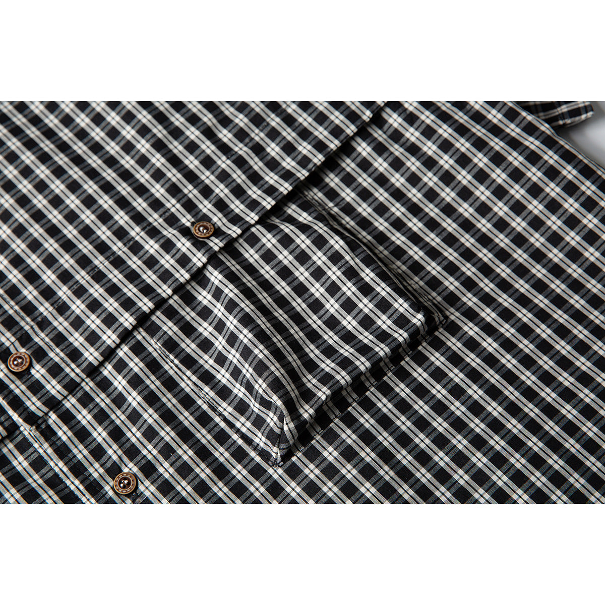Close-up of the black-and-white plaid shirt's button placket and chest pocket.