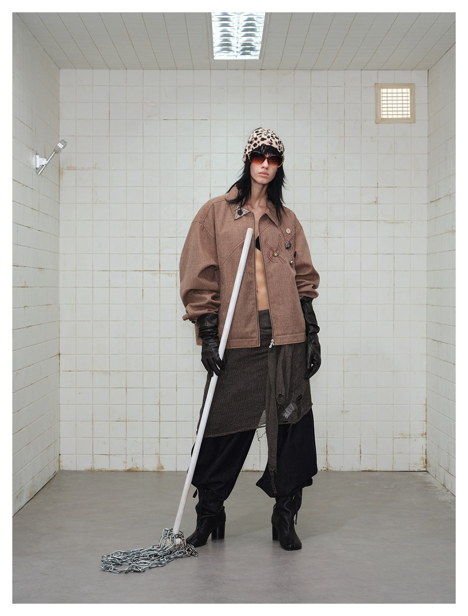Full-length front view of a model wearing an oversized brown jacket with dark layered clothing and boots.