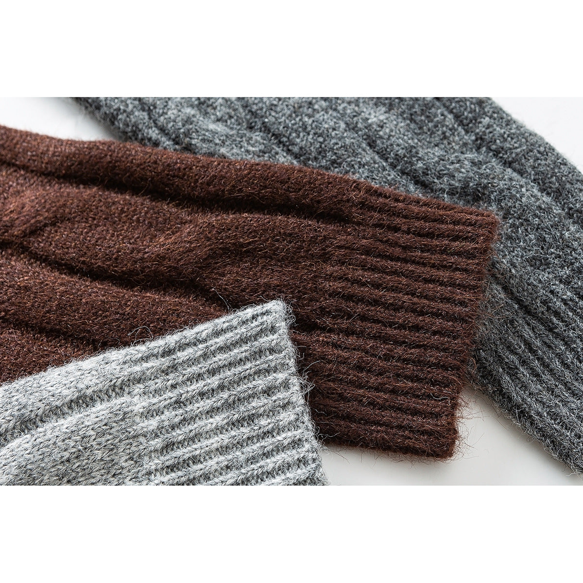 Close-up of ribbed cuffs on brown and gray cable-knit sweaters.