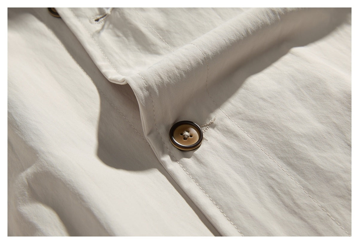 Close-up of an off-white garment's stitched placket and brown button.
