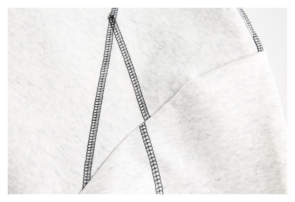 Close-up of black overlock seams crossing light gray garment fabric.