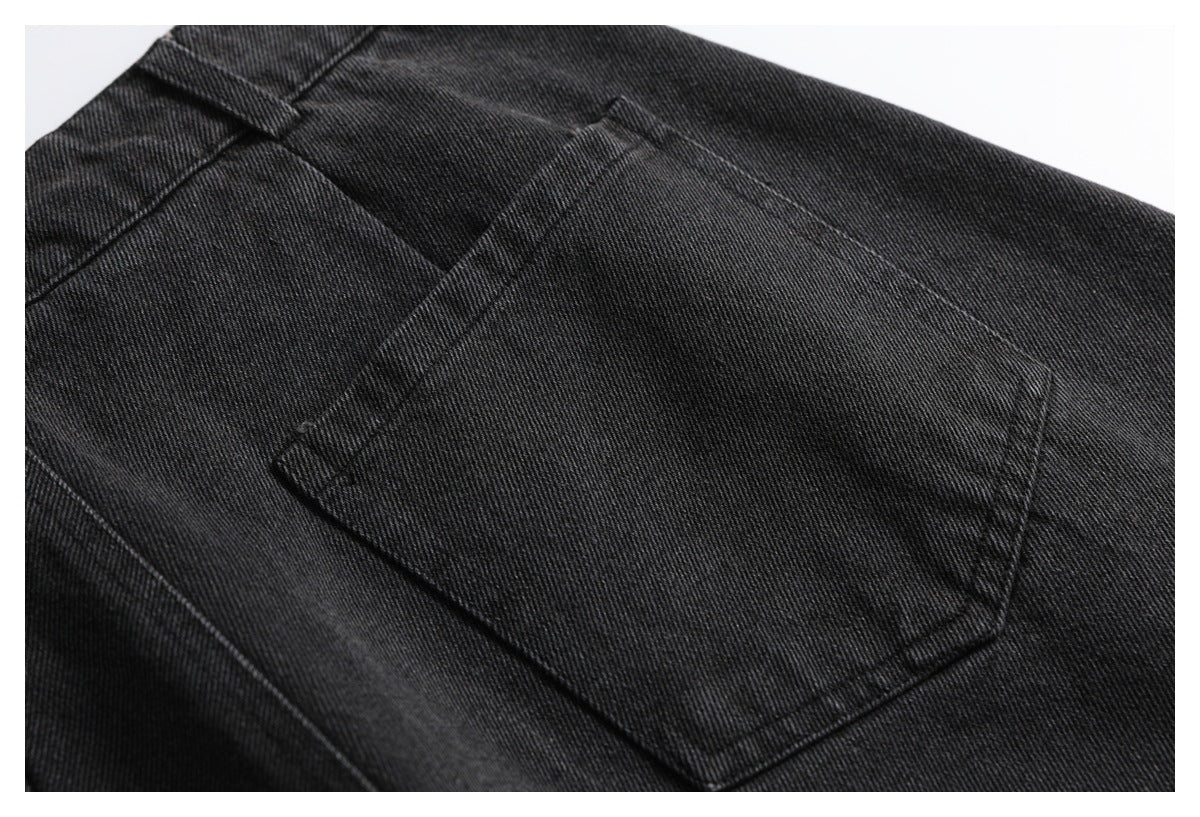 Close-up of a stitched back pocket on black denim trousers.
