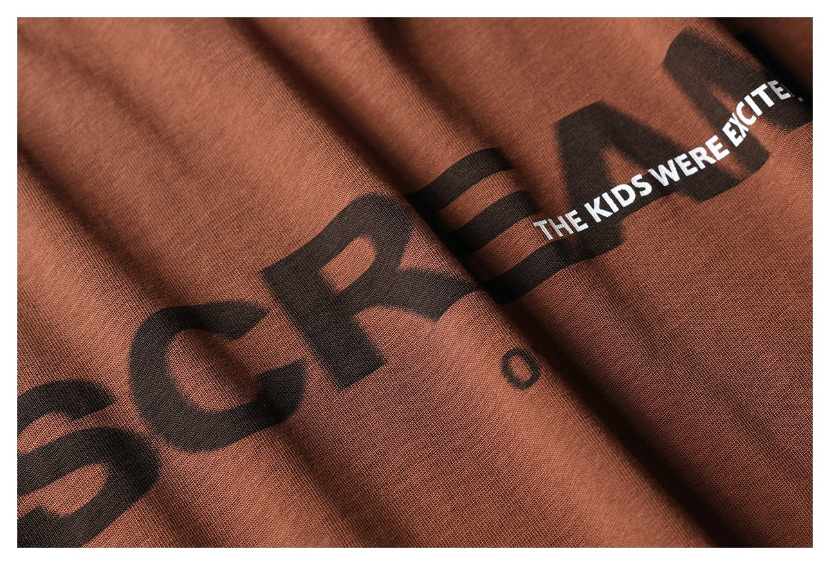 Close-up of rust-brown garment fabric with a black graphic and white printed English lettering.