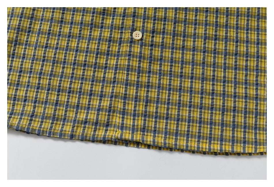 Yellow and navy plaid garment fabric with a cream button and a visible lower edge.