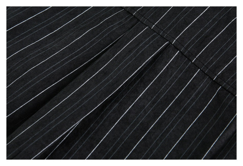 Close-up of black pinstriped garment fabric showing a stitched seam and folds.