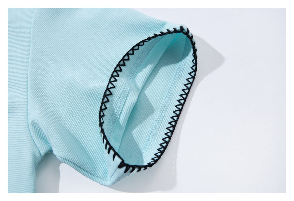Close-up of a light blue sleeve cuff with black zigzag edge stitching.