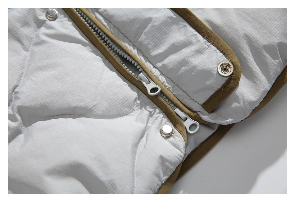 Close-up of the white quilted jacket front fastening, showing a zipper, metal snaps, and tan-brown trim.