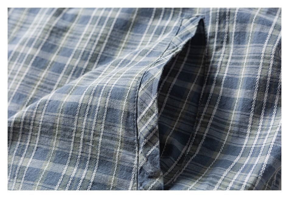 Close-up of a pocket opening on a blue-gray plaid shirt.