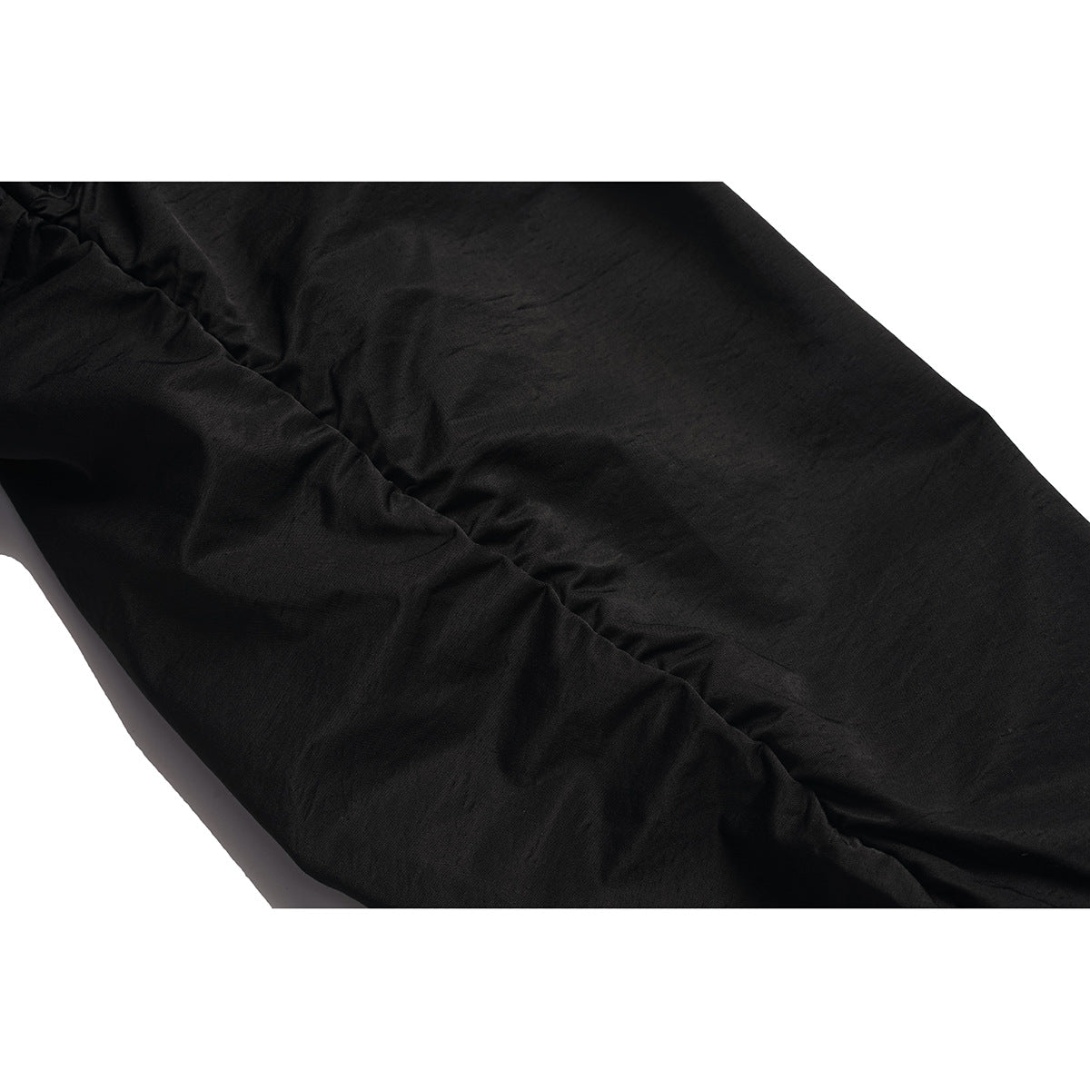 Close-up of black jacket fabric showing a gathered seam and stitching.