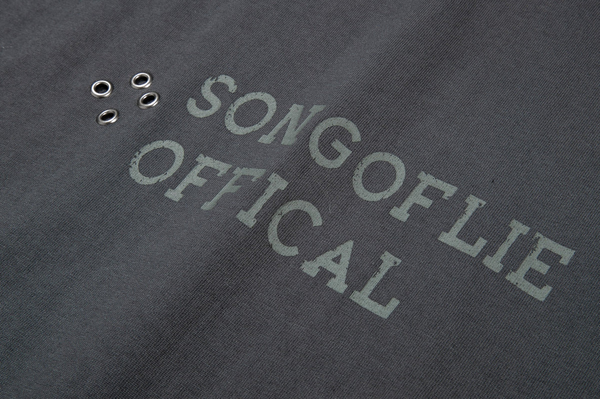 Close-up of a faded gray English text graphic and four metal eyelets on charcoal fabric.