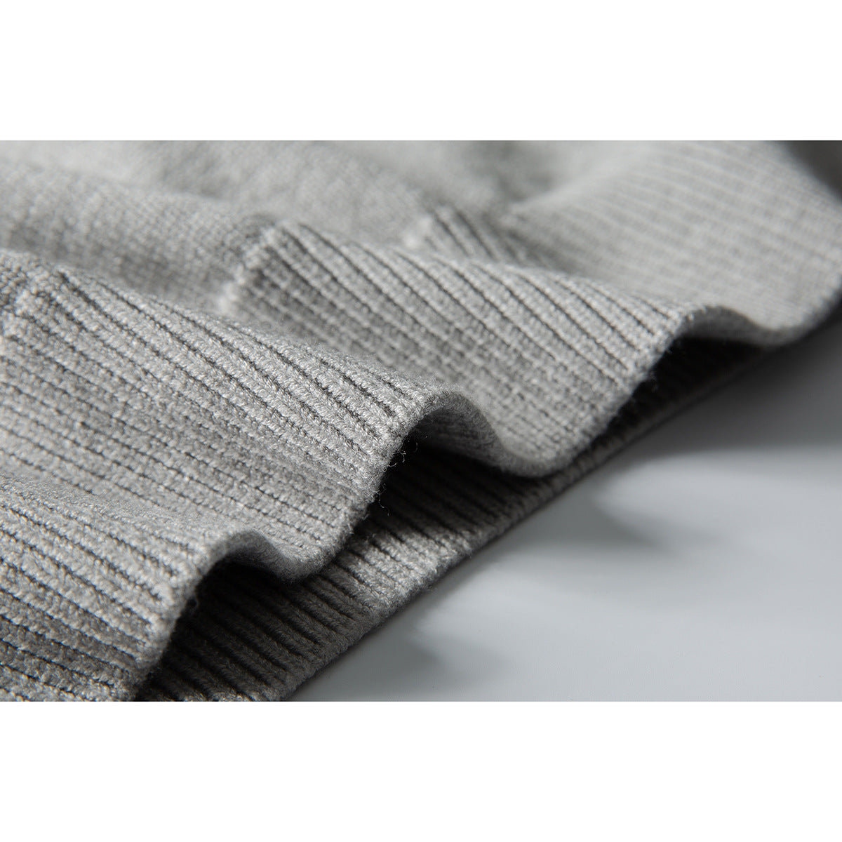 Close-up showing the textured knit and ribbed edge of a light gray sweater.