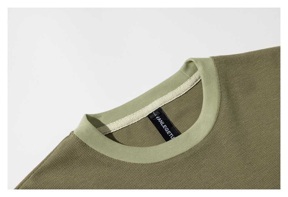 Close-up of the olive-green shirt’s ribbed crew neck and inner label.
