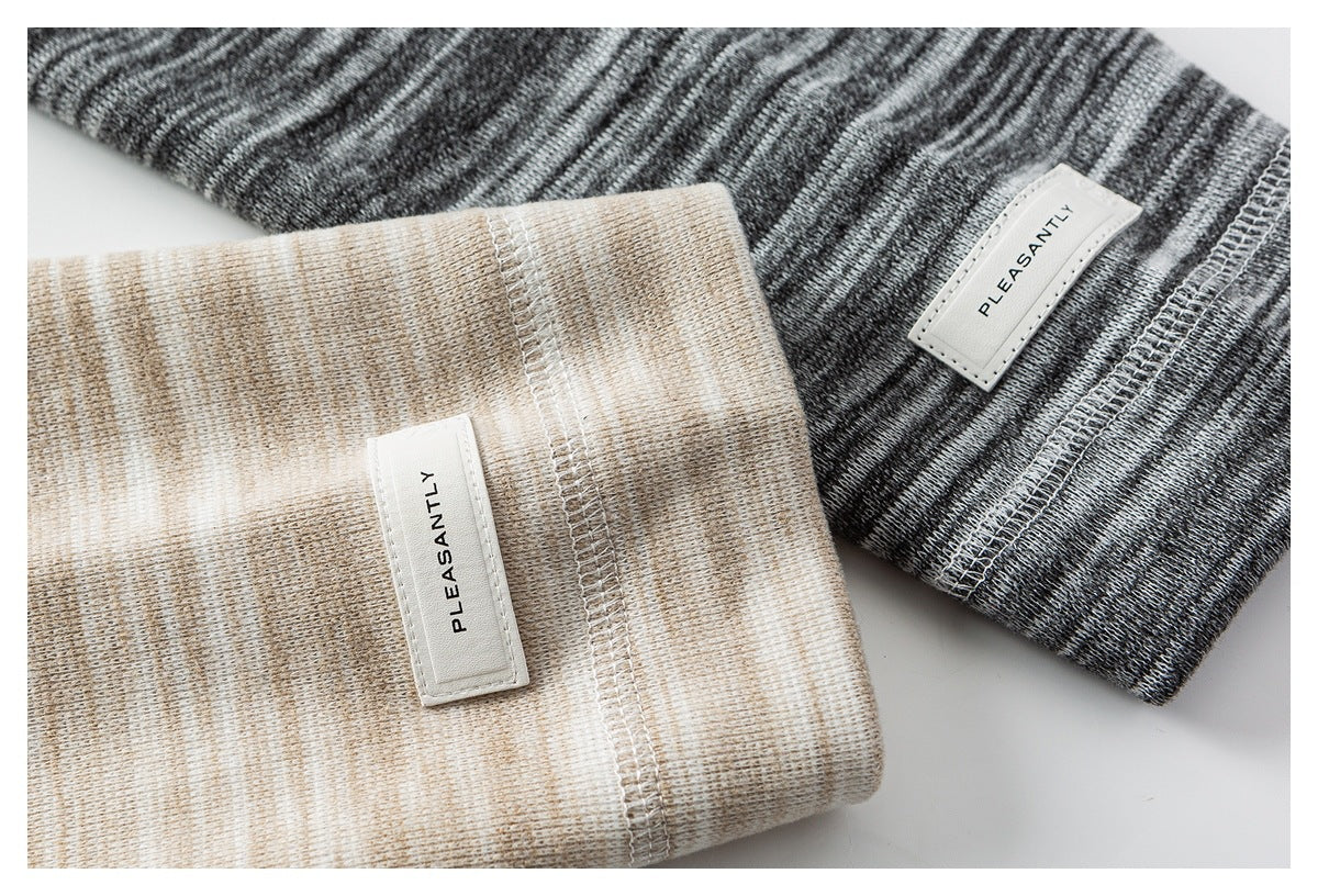 Close-up of beige and charcoal heathered knit cuffs with white sewn labels and visible stitching.