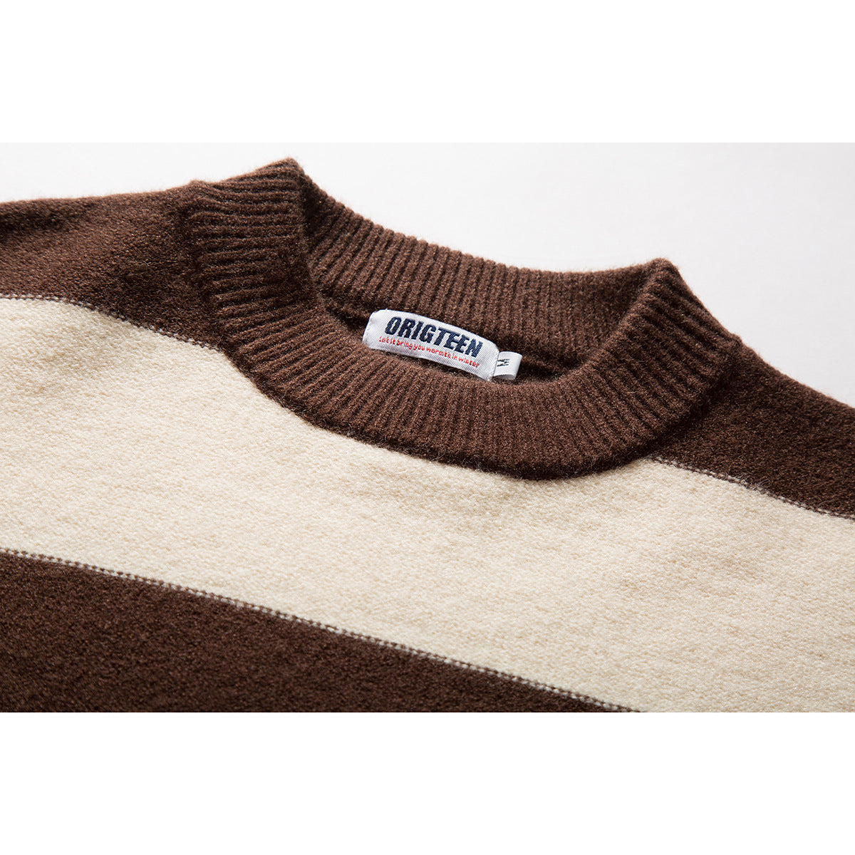 Close-up of a brown ribbed crew neckline and cream stripe on a brown-and-cream sweater, with a sewn-in label.