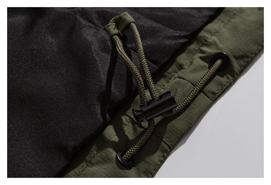 Close-up of an olive garment hem with braided drawcords and black cord locks beside dark lining.