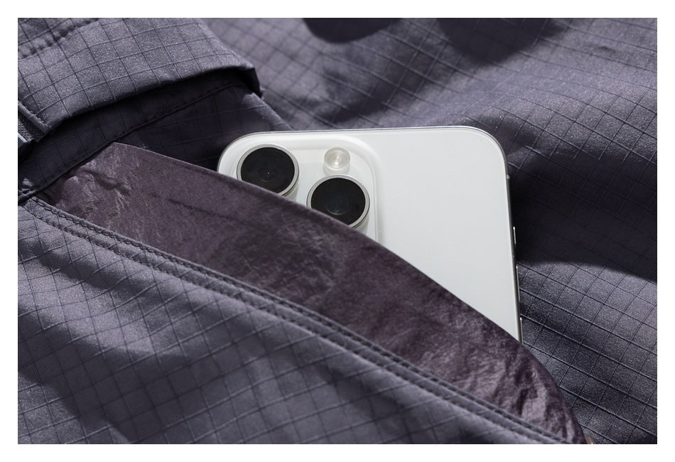 A white smartphone tucked into a pocket of a charcoal grid-pattern jacket.