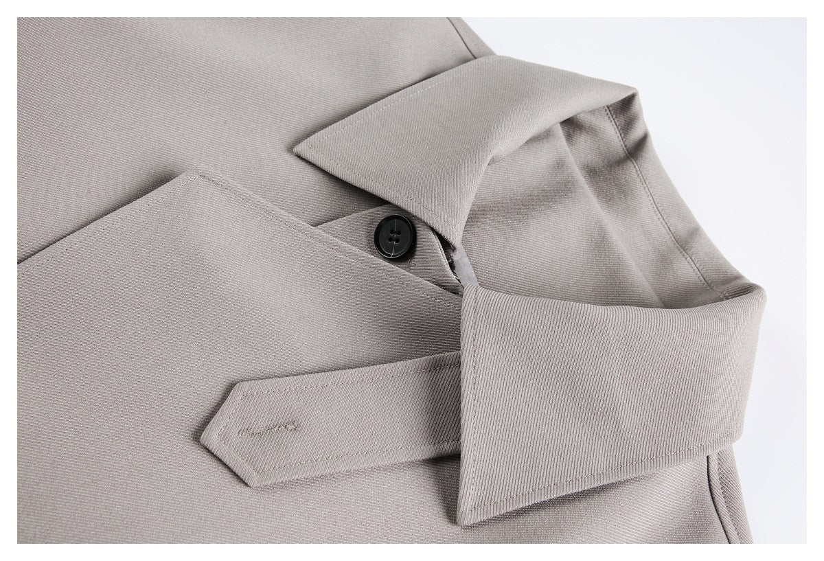 Close-up of a light gray cuff with a wide folded strap and black button.