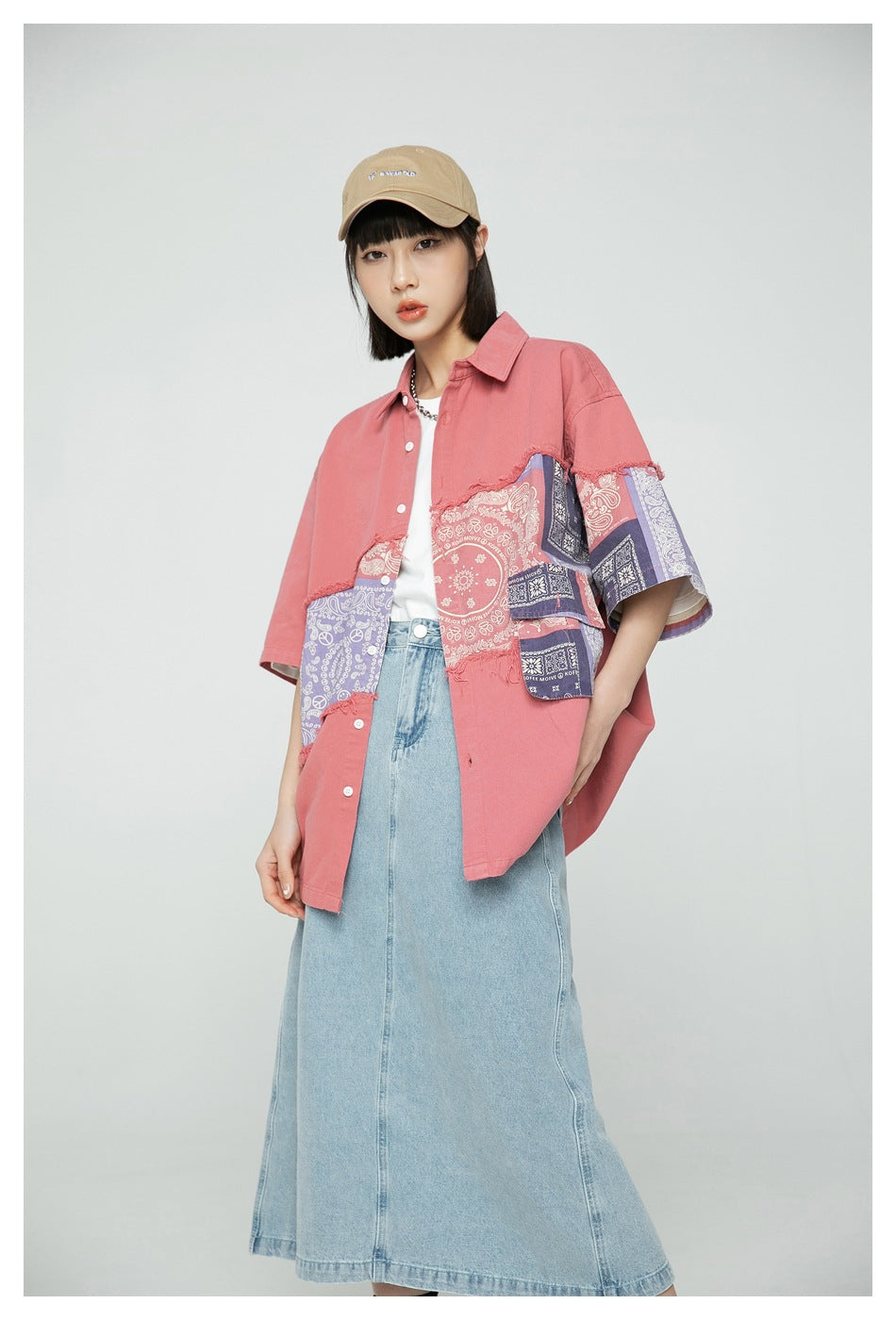 Closer front view of a model wearing a coral oversized shirt with purple and coral paisley patchwork panels.