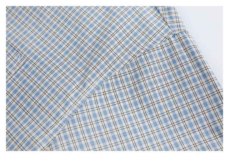 Close-up of light blue, white, and black plaid shirt fabric with a diagonal stitched seam.