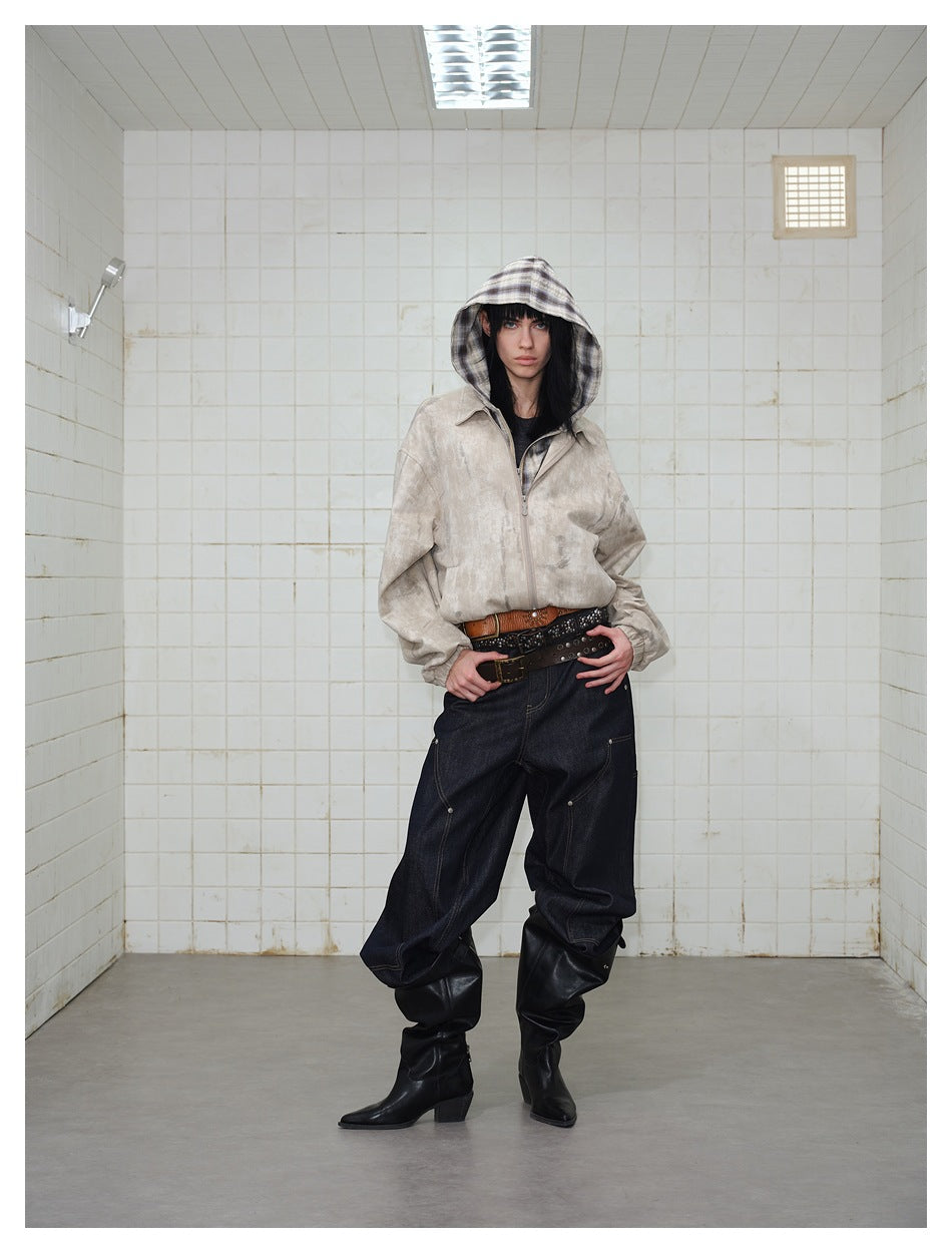 Front view of a model in a light beige mottled zip jacket with a plaid hood and dark baggy jeans.