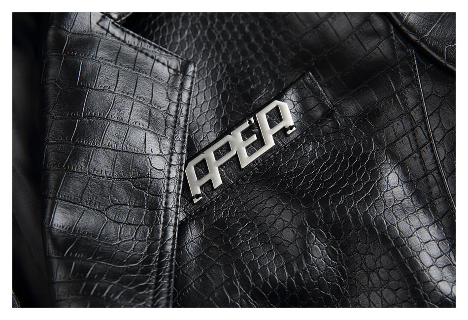 Close-up of a silver-tone geometric metal emblem on the black jacket's crocodile-textured lapel.
