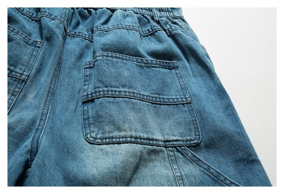 Close-up of a patch pocket and seam on the back of blue denim bottoms.