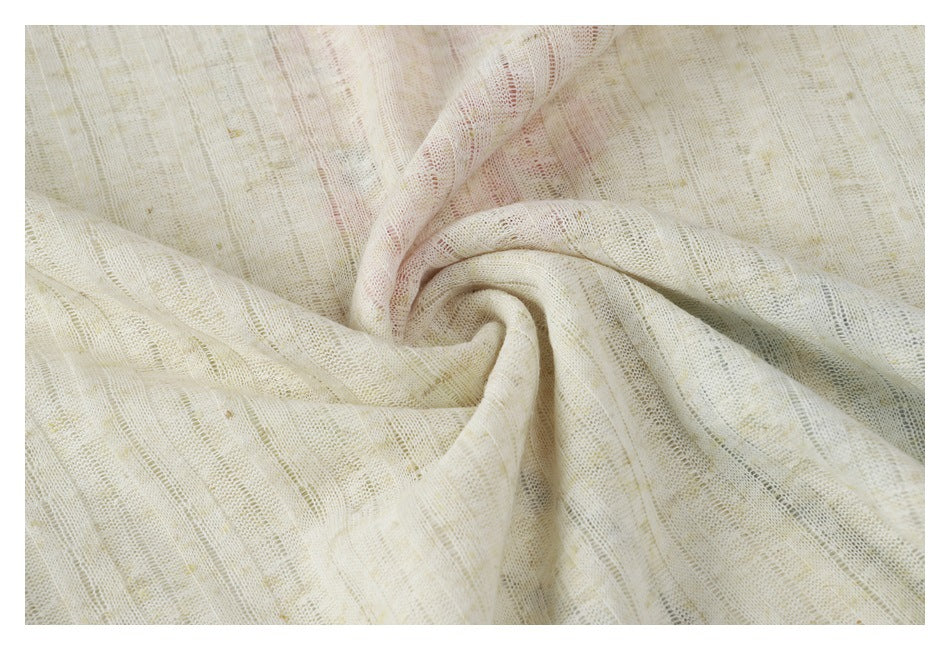 Close-up of cream textured fabric gathered into soft folds, showing its open-knit pattern.