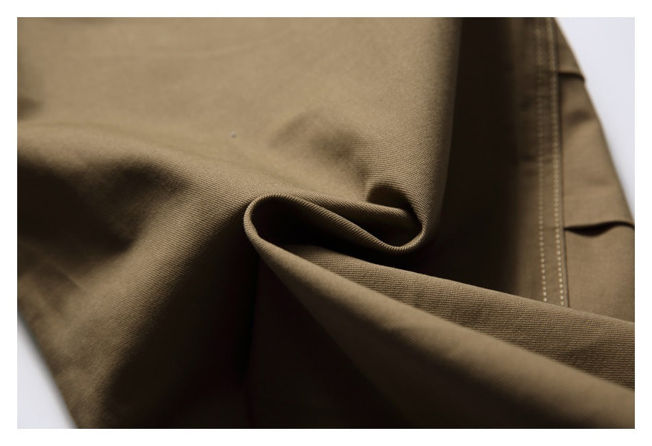 Close-up of brown fabric showing its fine weave, folds, and a stitched seam.