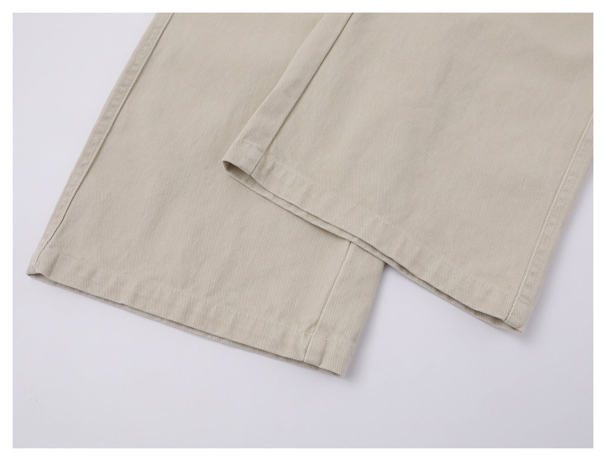 Close-up of the straight hems on beige trouser legs.