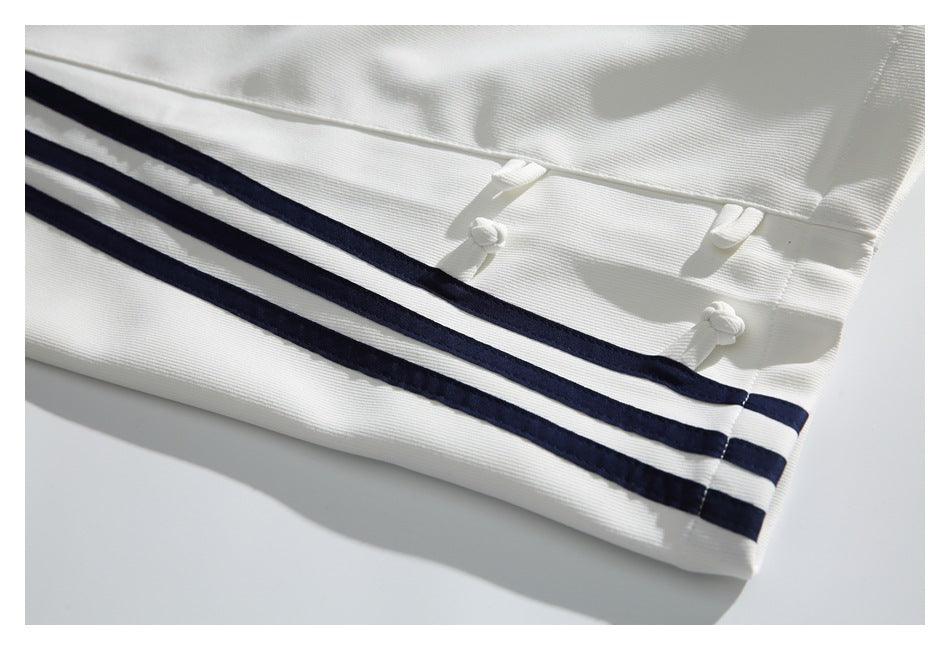 Close-up of white trousers showing a pocket, knotted details, and navy side stripes.