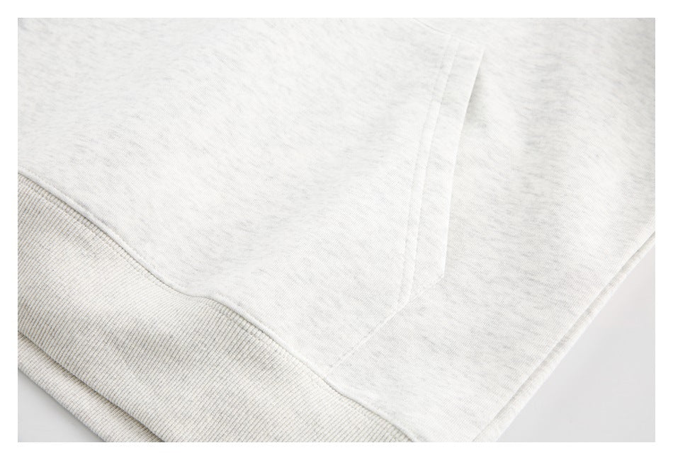 Close-up of a light heather-gray sweatshirt hem with wide ribbed trim and stitching.