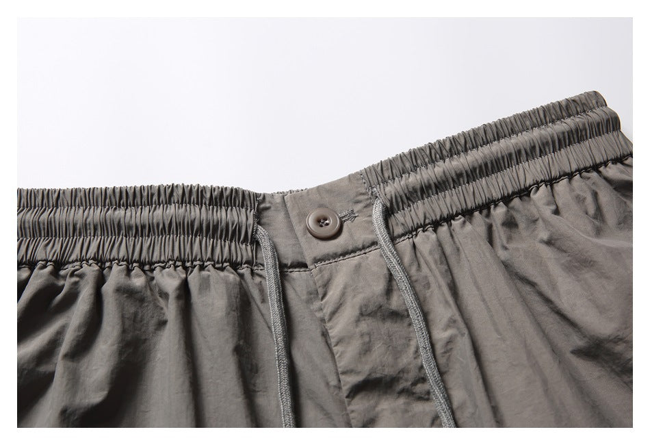Close-up of the shorts' elastic waistband, button closure, and gray drawstrings.