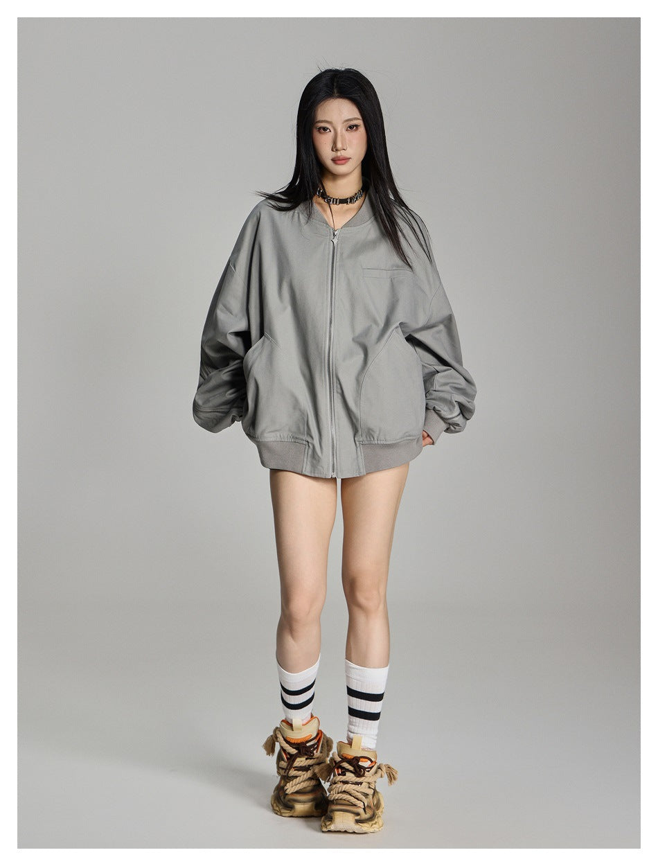 Full-length view of a model wearing a light gray oversized zip-front jacket with roomy sleeves and curved pockets.