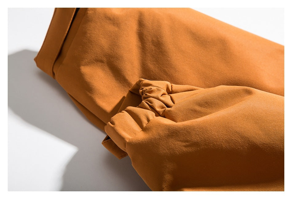 Close-up of an orange jacket sleeve with a gathered elastic cuff.