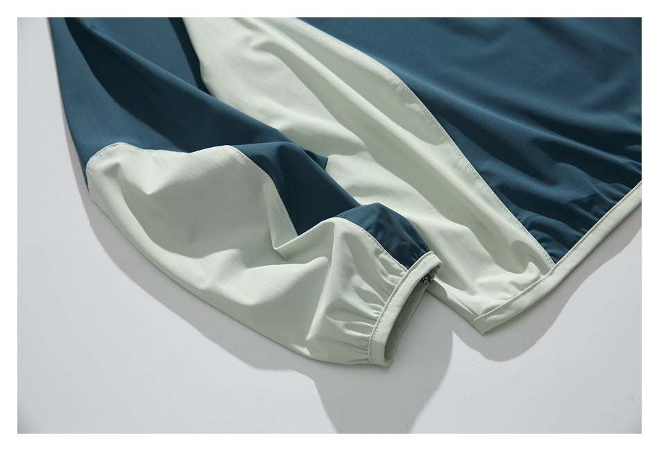 Close-up of a teal and pale mint color-blocked garment with a gathered cuff and stitched edges.