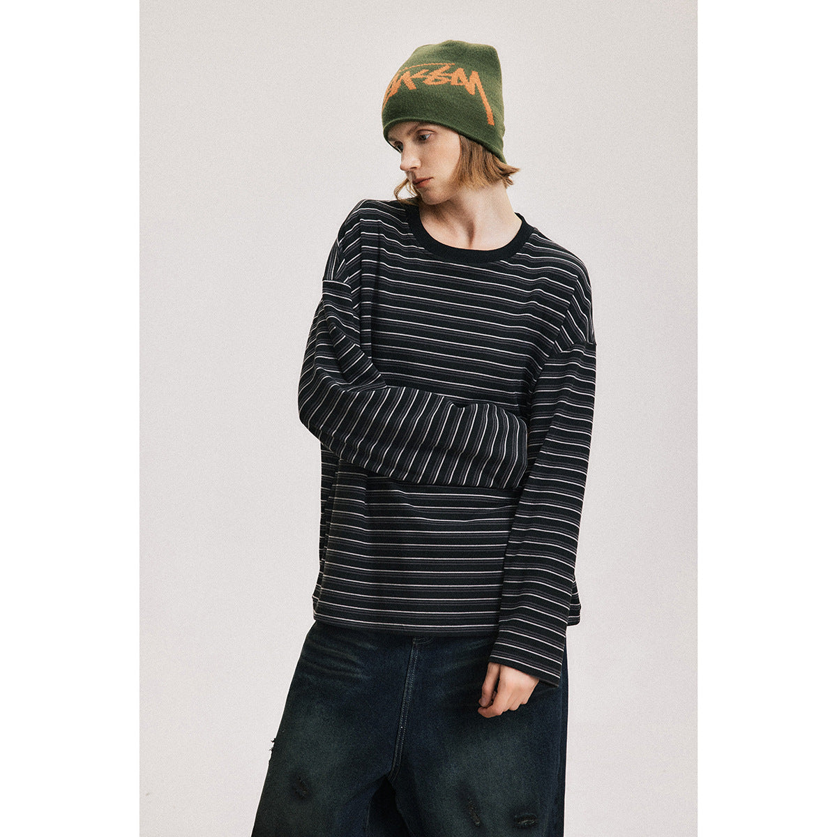 Model wearing a black long-sleeve shirt with thin white stripes and dark jeans.