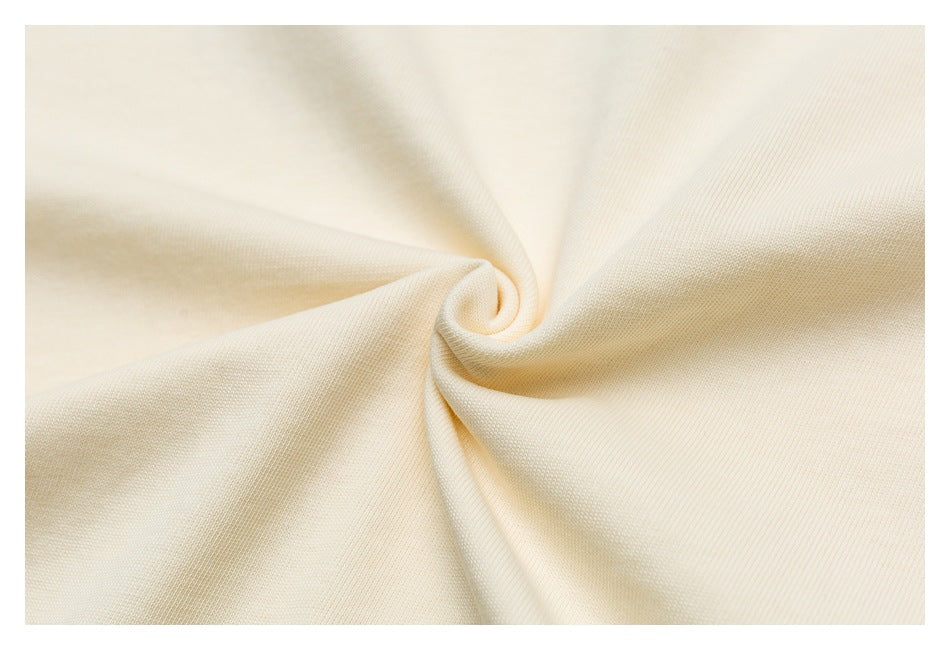 Close-up of cream-colored fabric gathered into a swirl, showing its surface texture.