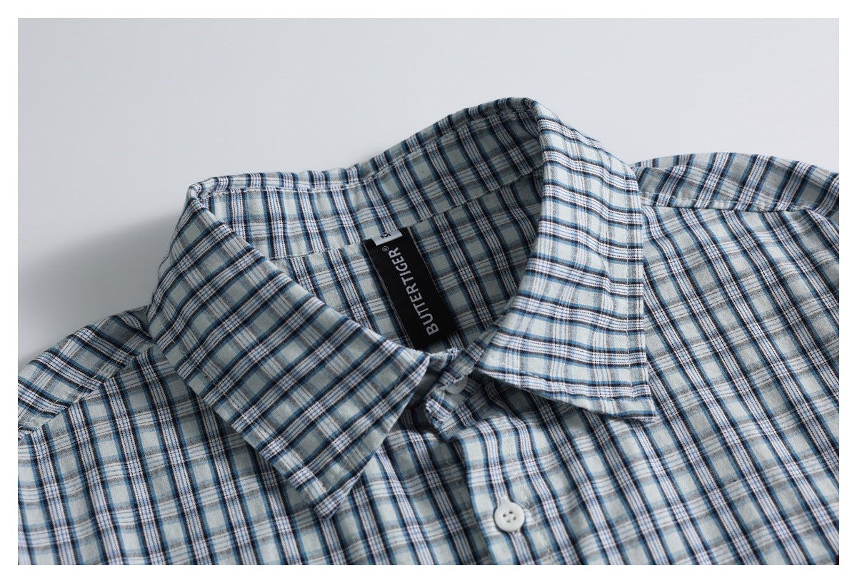 Close-up of a blue, gray, and white plaid shirt collar, placket, and black neck label.