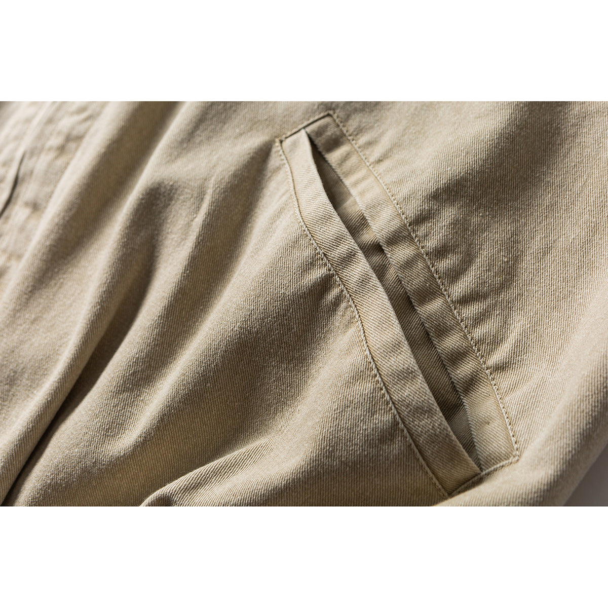 Close-up of a slanted welt pocket on beige jacket fabric.