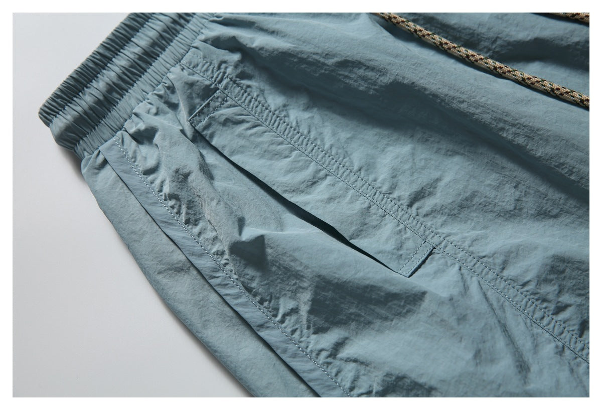 Close-up of the elastic waistband and angled pocket stitching on blue-gray shorts.