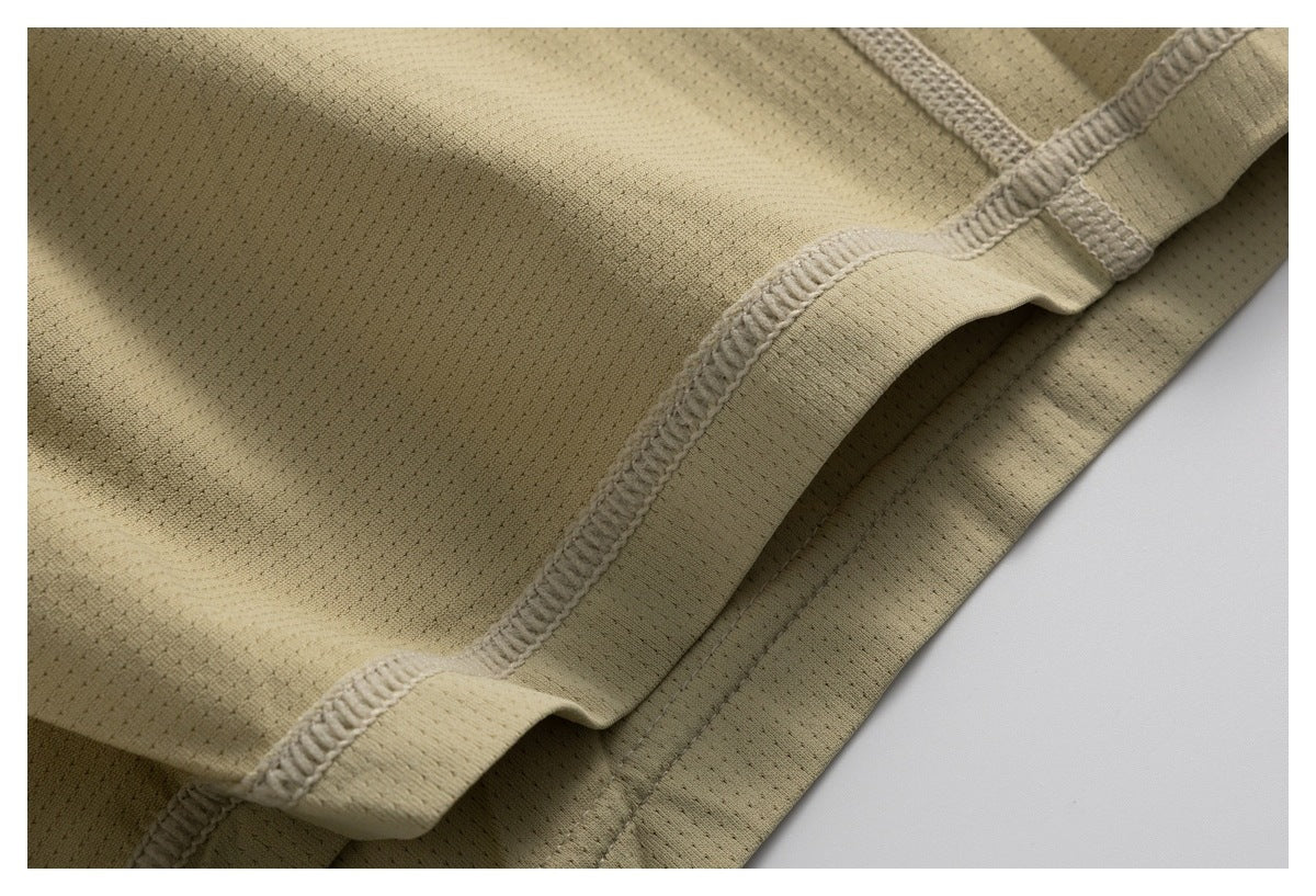 Close-up of beige mesh fabric with a folded hem and visible overlock stitching.