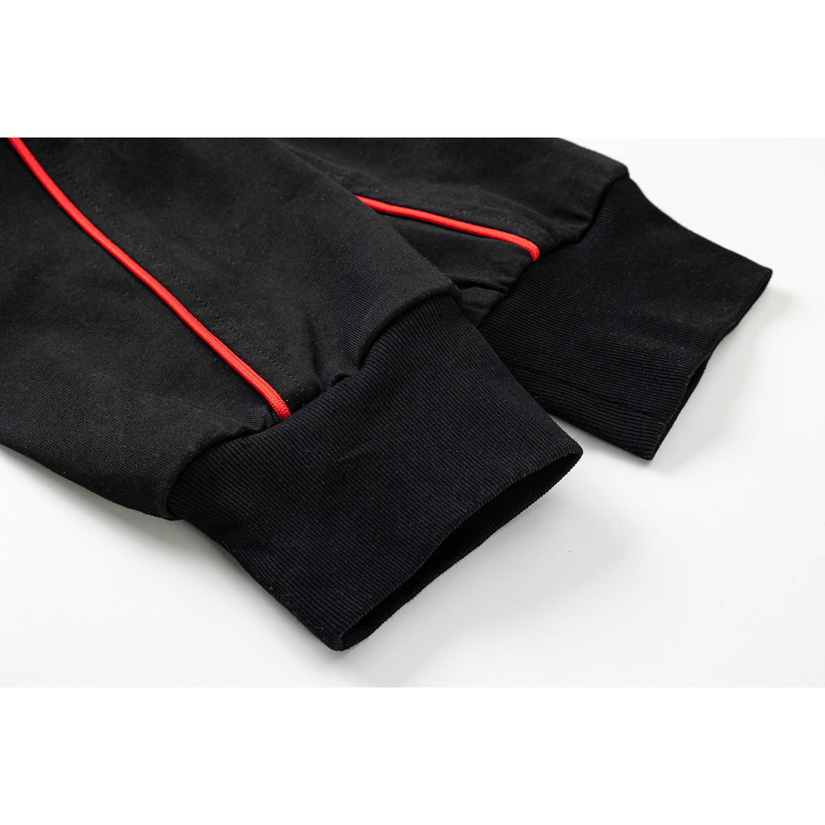 Close-up of black shirt sleeves with wide ribbed cuffs and bright red piping.
