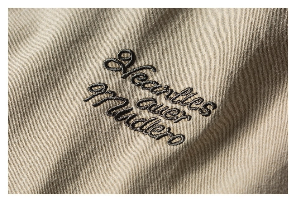 Close-up of black cursive words embroidered on beige twill fabric.