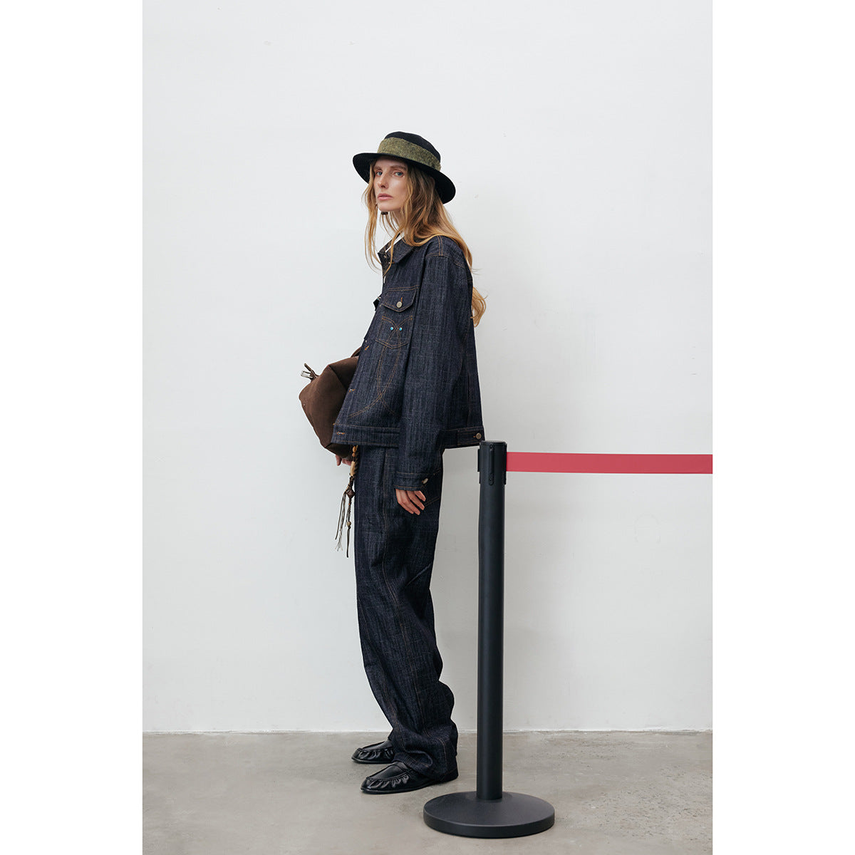 Side view of a model wearing a dark indigo jacket and loose matching trousers with decorative stitching.
